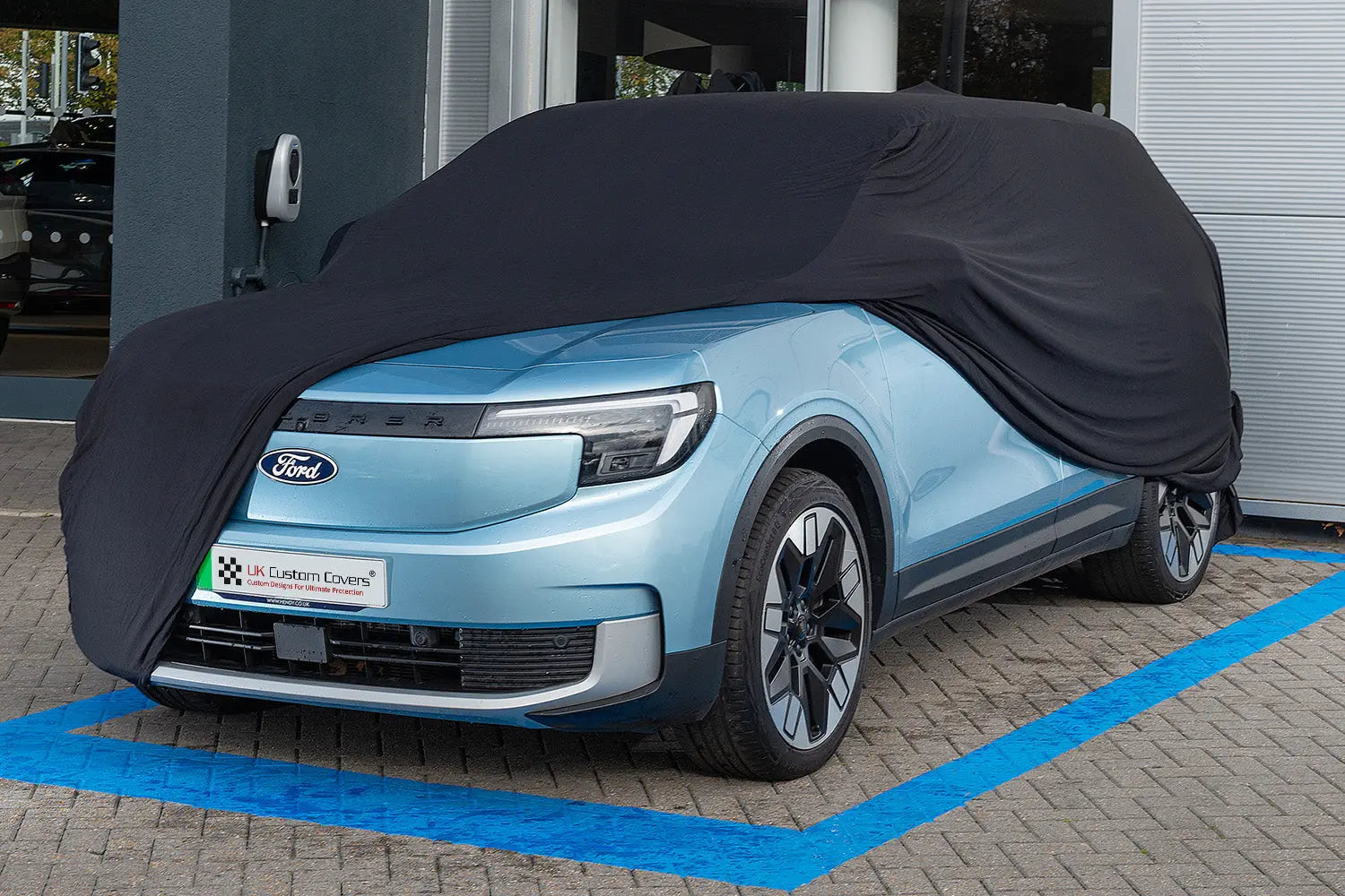 Blue Ford Explorer outside with a black indoor car cover over the top showing the front of the car 